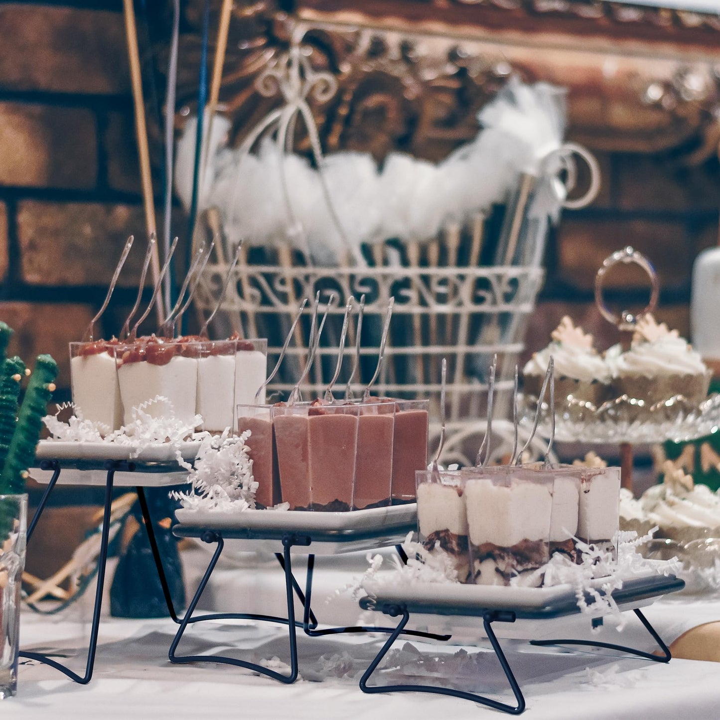 Decorative dessert display with various treats on a stand against a rustic brick wall.