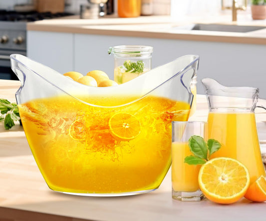 Clear glass pitcher filled with orange juice on a kitchen counter, with lemons and a glass of juice.