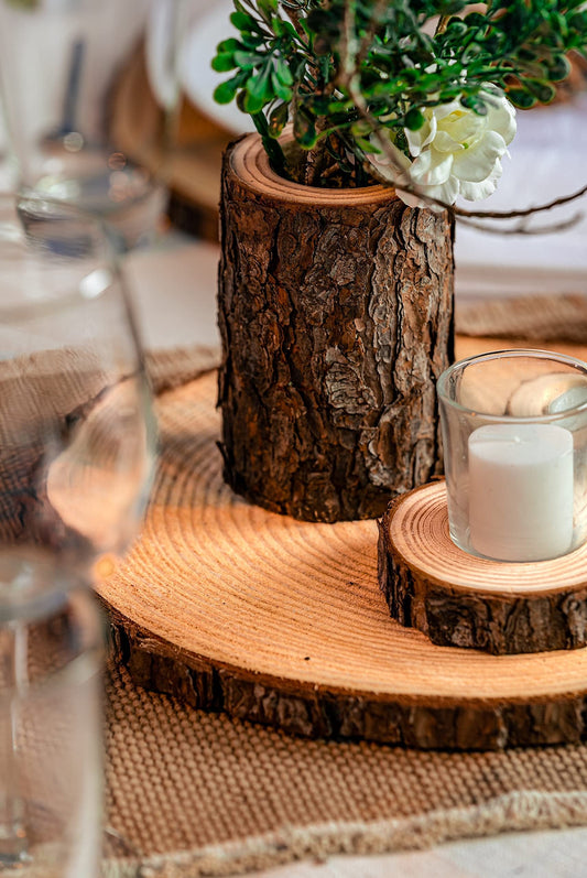 Decorative setting with a wooden log slice, small tree stump planter, and candle on a table.